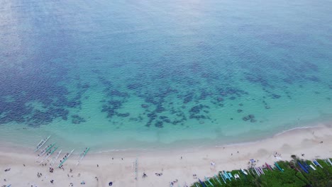 Drohnenaufnahmen-Beginnen-Am-Strand-Von-Lanikai-Auf-Der-Insel-Oahu,-Beginnend-Am-Weißen-Sandstrand-Mit-Auslegerkanus-Und-Hinaus-Ins-Blaugrüne-Wasser-Mit-Korallenriffen