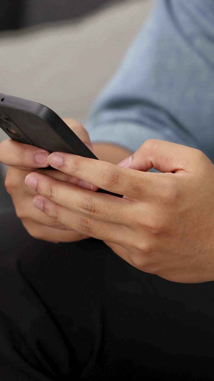 Primo piano di mani che digitano e scorrono su uno smartphone con una luce naturale soffusa.