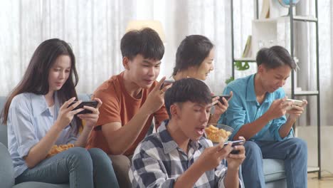 asian teenagers playing video games on smart phone at home.