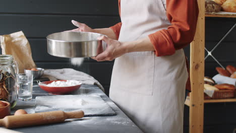 female baker sifting flour on table