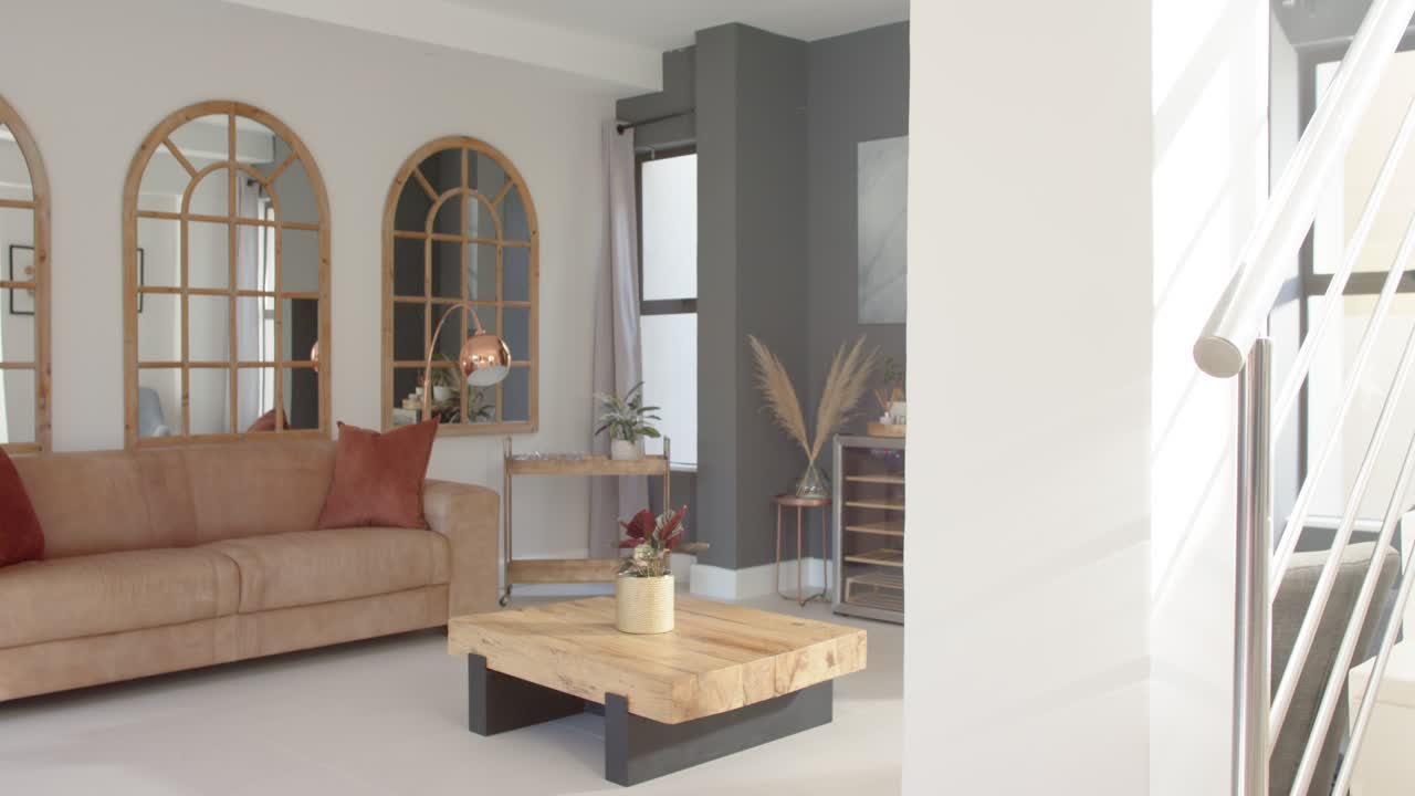 La caméra effectue un panoramique vers la gauche, dévoilant le coin salon du séjour pour mettre en valeur le canapé, la table et la décoration.