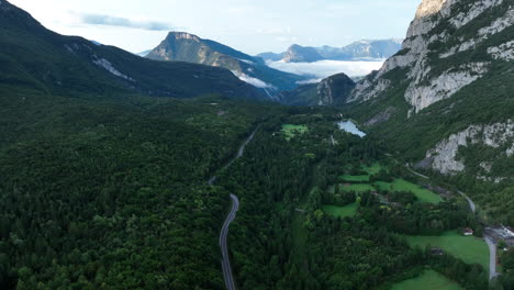 Winding-road-leading-through-forestry-valley-of-Dolomites,-aerial-view