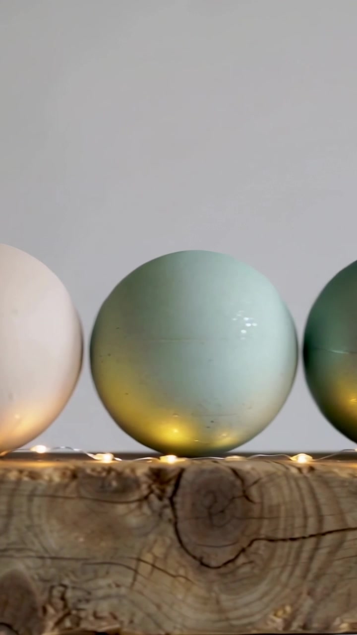 Vertical video: Panning camera revealing matte ornaments on wooden beam, highlighting warm LED glow