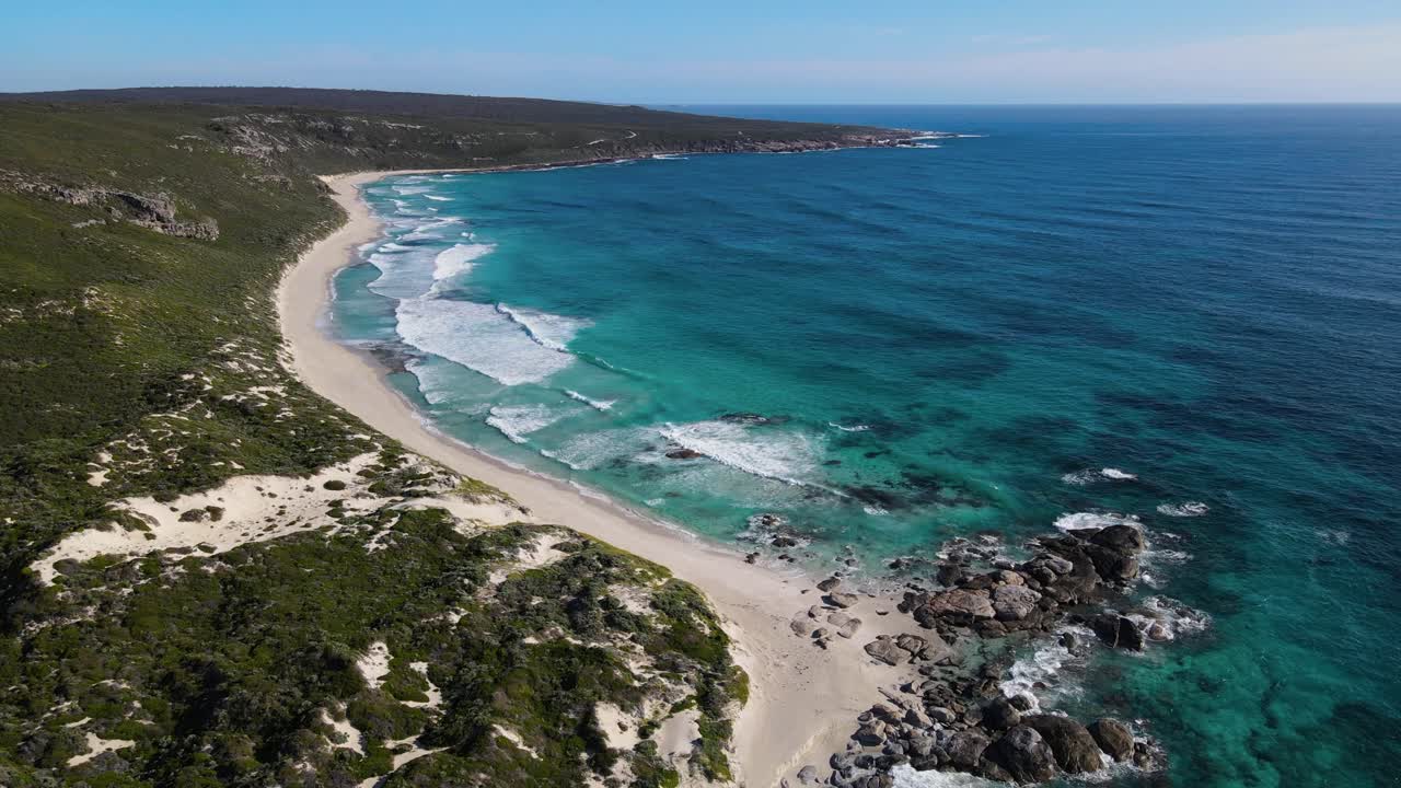 Volo aereo con vista dall'alto di un'idilliaca spiaggia rocciosa deserta con acqua turchese e sabbia bianca, un Paradiso.