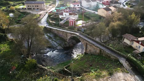 Das-Licht-Des-Frühen-Morgens-Glitzert-Auf-Einer-Dreieckigen-Brücke-Mit-Großer-Öffnung-über-Dem-Fluss-Lonia,-Luftparallaxe