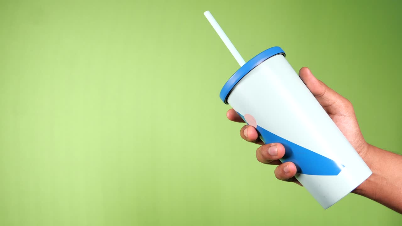 초록색 배경에 재사용 가능한 생태 커피 컵을 들고 있는 손