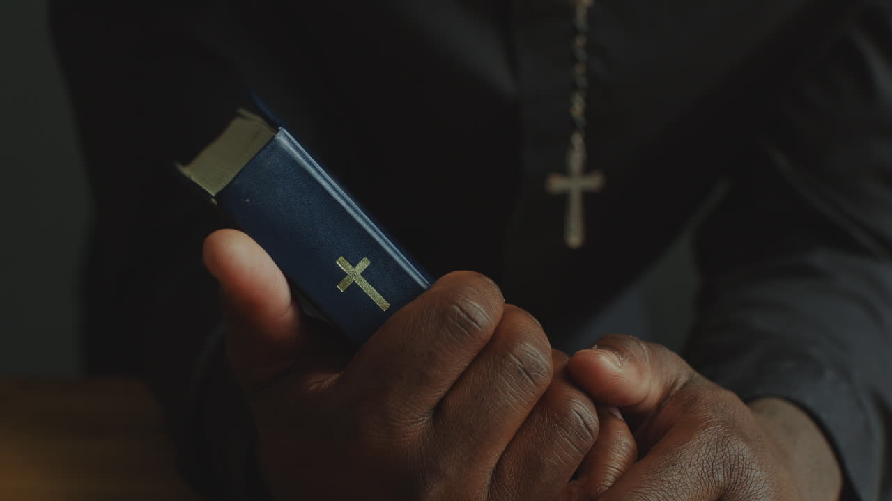 Mani di un sacerdote che tiene la Sacra Bibbia sull'altare in chiesa