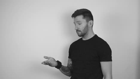 imágenes en escala de gris de un hombre tatuado girando una moneda de bitcoin en cámara lenta arrojándola al aire y atrapándola. después de atraparla el tipo muestra la moneda a la cámara mientras mira directamente.