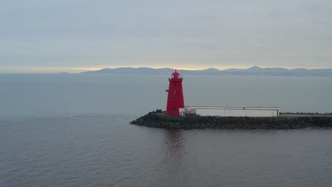 Luftaufnahme-Vom-Leuchtturm-Von-Poolbeg-Mit-Gelbem-Schein-Am-Horizont-Unter-Bewölktem-Himmel