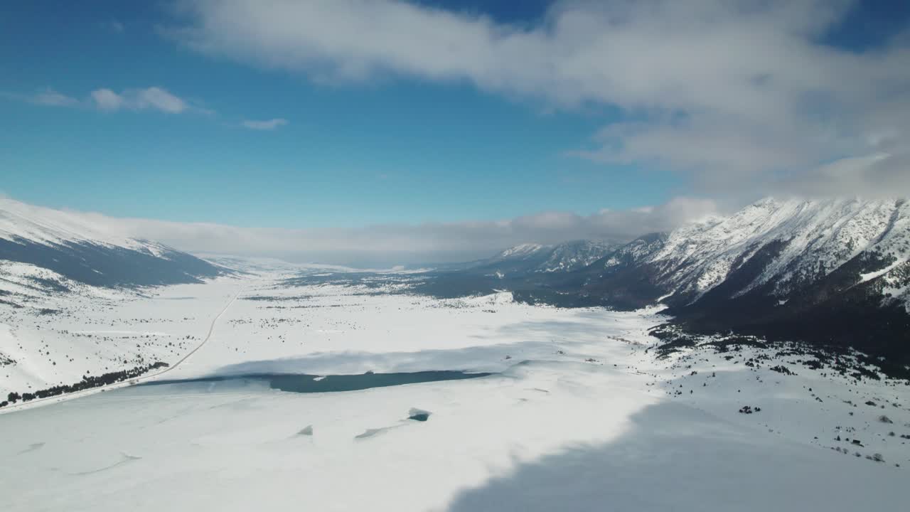 fotografía de un lago congelado, rodeado de montañas en un hermoso día soleado