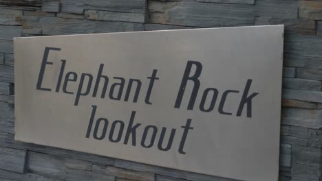 woman passes by in front of the elephant rock lookout signage near the currumbin beach - gold coast, queensland, australia - close up shot