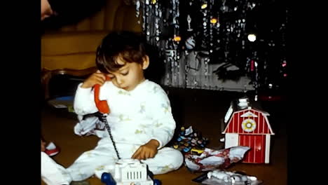 young boy sitting on couch with toy. circa usa - 1970s: a little boy from a 1970s video archive in the usa sitting on a couch while playing with a toy.