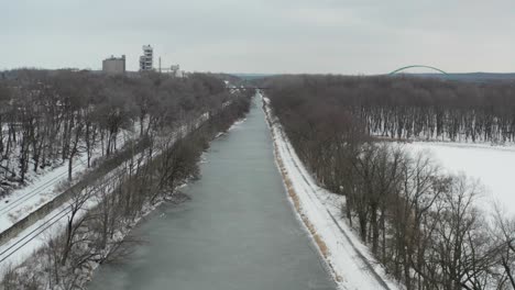 ascending over frozen river revealing city buildings in distance