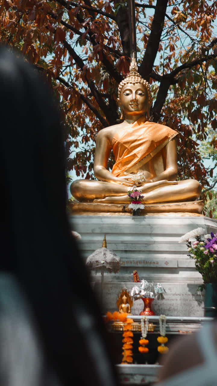 Statua dorata di Buddha con offerte in un tempio buddista