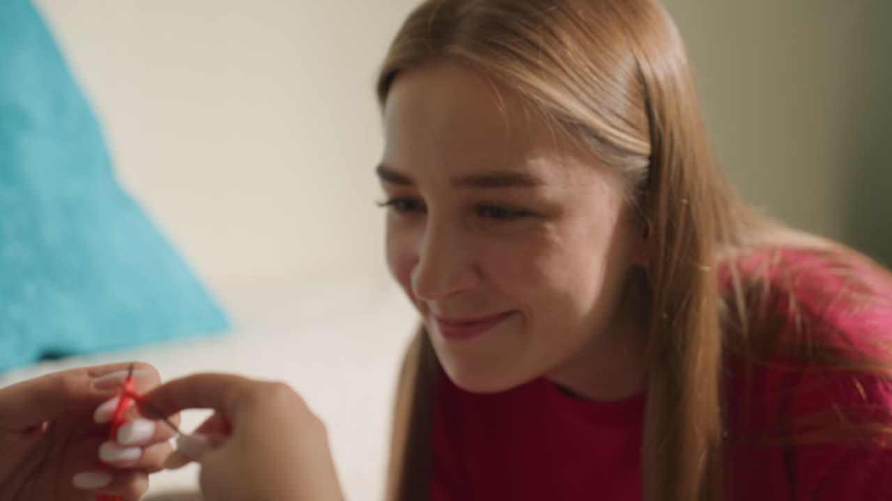 amigo examina un objeto, primer plano de la interacción de la mano y la cara, curiosidad divertida durante una escena de inspección acogedora en el dormitorio, un momento íntimo con una mujer que inspecciona cuidadosamente un pequeño objeto rojo