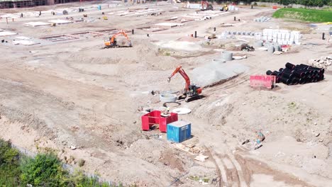 heavy construction machinery laying concrete waste pipes on real estate construction site aerial view