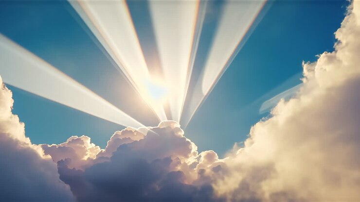Casting central sun breaking through cumulus cloud bank over blue sky, producing multiple sunbeams