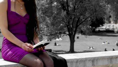 Niña-Bonita-Leyendo-En-Un-Cuaderno-Frente-Al-Parque,-Entorno-Educativo,-Universidad