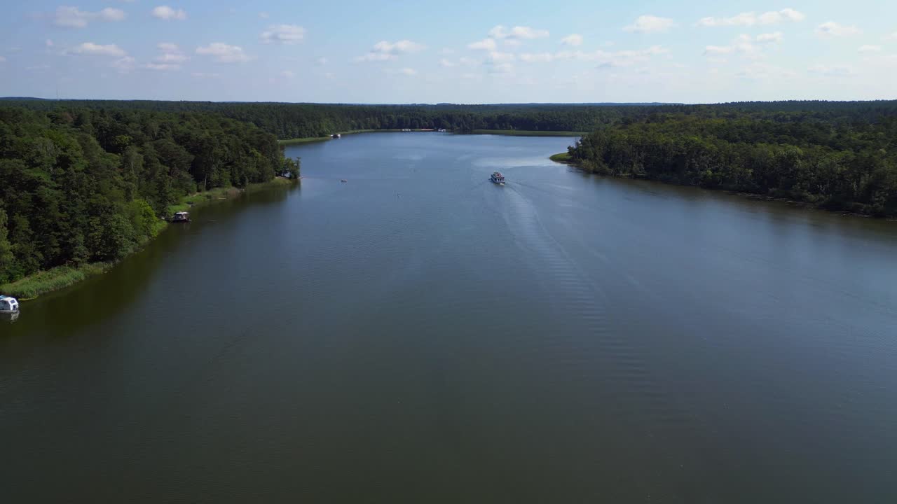 passenger ferry boat on a calm lake surrounded by green forest on a sunny summer day in germany. Fabulous aerial view flightfly push forward drone