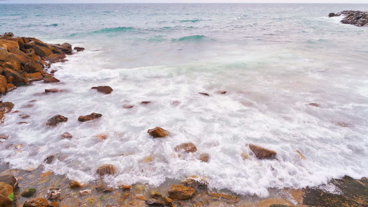 Costa sul Mar Mediterraneo in Italia. Cielo nuvoloso, onde, rocce sulla spiaggia