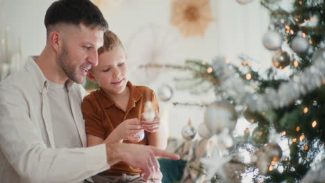 papá y hijo pequeño se preparan para las fiestas y decoran el árbol de navidad