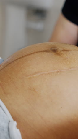 doctor's hand moving ultrasound transducer by the big pregnant belly of an unrecognized woman. checking the pregnancy on the last stages before baby delivery. vertical video