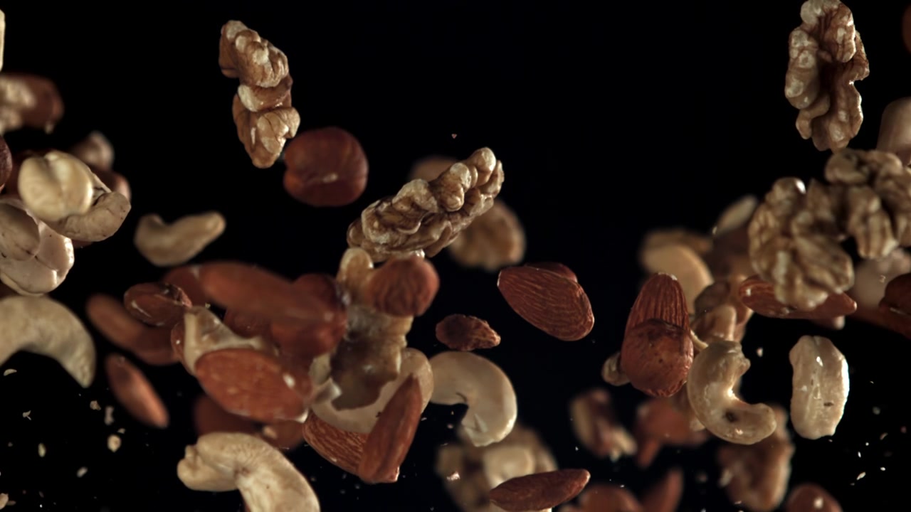 Mixed Nuts Falling in Slow Motion Against a Black Background