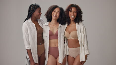 three young women in bras and white shirts laugh together