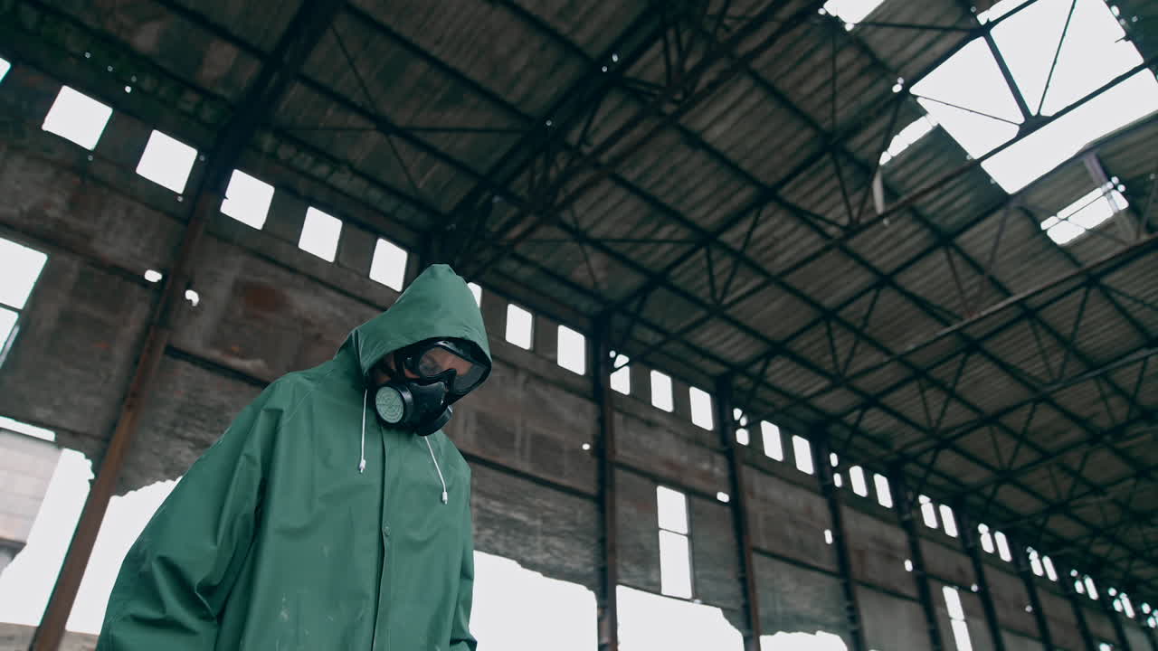 Person in protective uniform and gas mask. Polluted zone after chemical attack emissions. Woman wearing hazmat suit on the background of destroyed building.