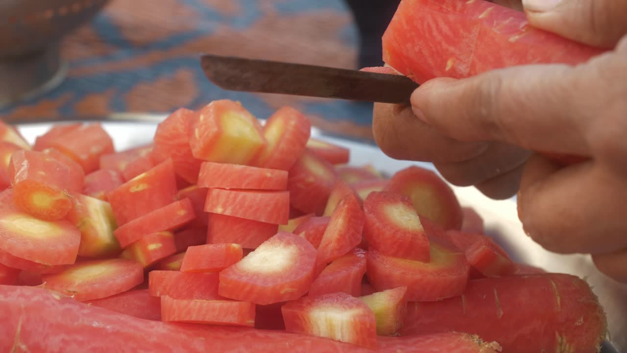 Closeup of cutting fresh orange carrots into small pieces