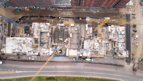 overhead shot of intricate construction site with cranes and workers in urban area