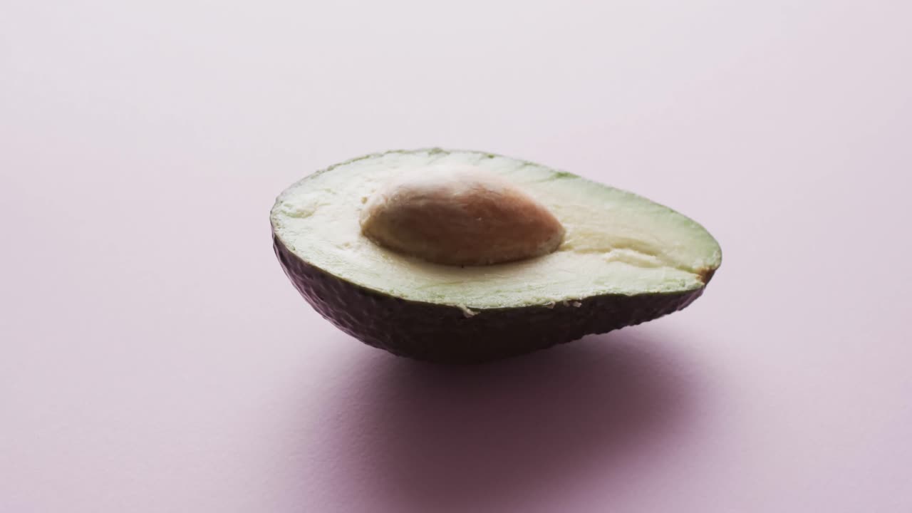 Video av skivet avokado med tekstplass på rosa bakgrunn