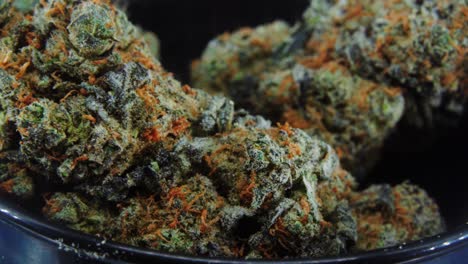 Macro-Purple-Green-Dried-Marijuana-Buds-Close-Up-concept-Shot,-pile-of-dried-marijuana-plants,-orange-trichomes-strains,-in-small-black-shiny-bawl,-on-a-rotating-stand,-studio-lights,-slow-motion,-4K