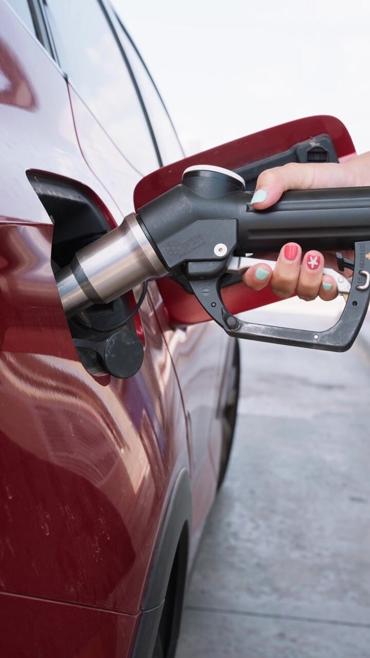 Woman Refueling Red Car at Gas Station