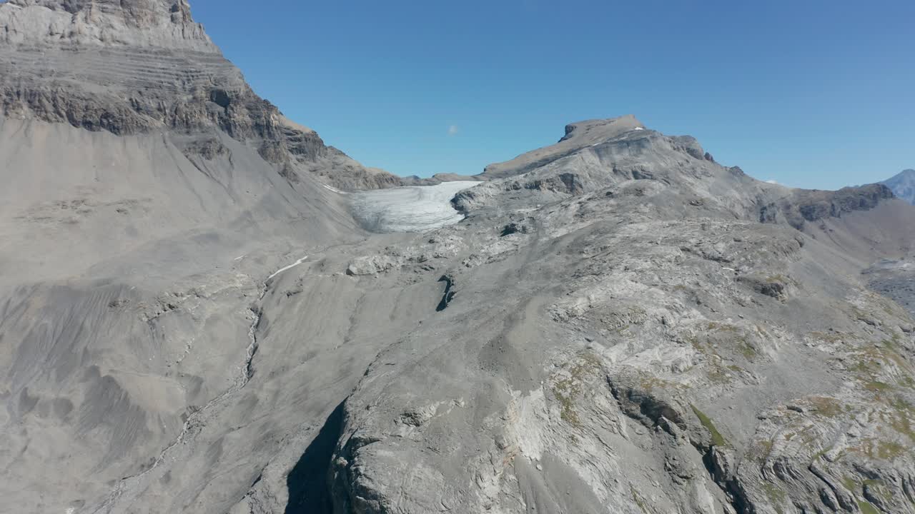 drone volando lentamente hacia un glaciar casi derretido en la montaña
