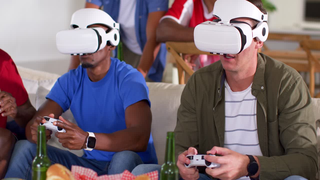 Vertical video: Game starting two men in white VR headsets on sofa using controllers, raising hands