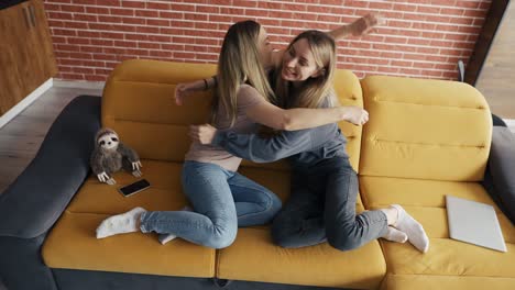 Zwei-Glückliche-Freunde-Sitzen-Auf-Einer-Couch,-Schließen-Ihren-Laptop-Und-Umarmen-Sich