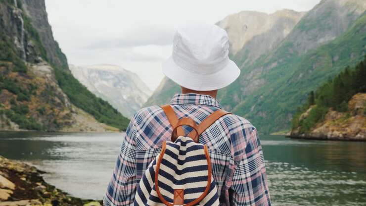 Eine Frau mit Rucksack auf dem Rücken blickt auf den majestätischen Fjord in Norwegen. Reisen und Tourismus.