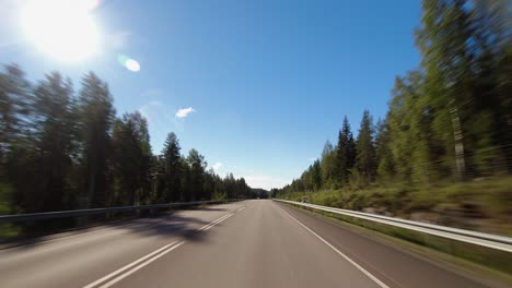 blue sky driving pov on highway through northern evergreen forest