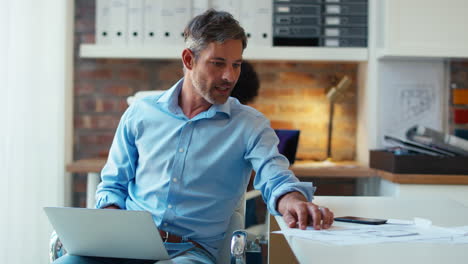 mature businessman using laptop working at desk in modern office