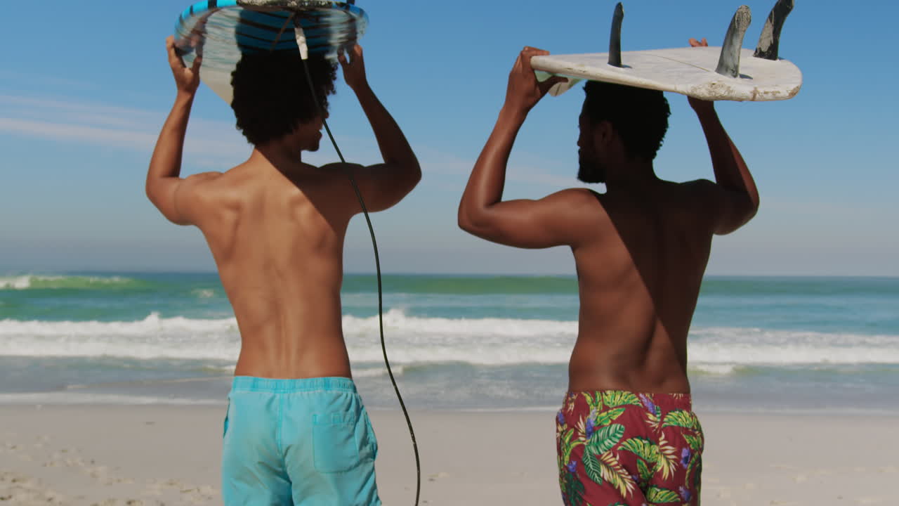 Giovani amici che trasportano una tavola da surf sulla testa 4k