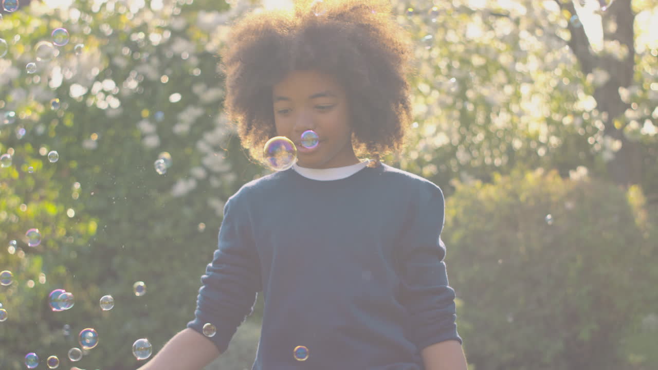 Smiling Boy Outdoors Having Fun Playing With Bubbles In Garden