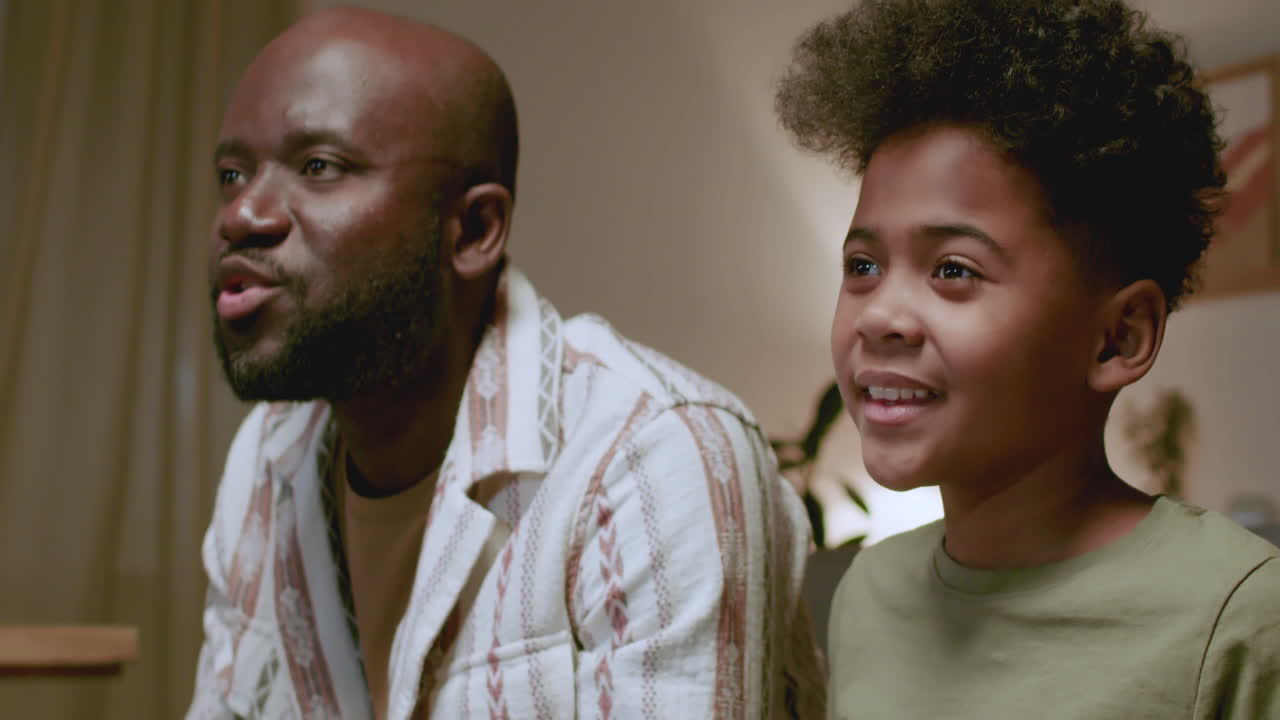 чернокожие мужчина и мальчик играют в видеоигры ночью