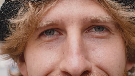 extreme closeup macro portrait of young face redhead mans eyes looking at camera smiling
