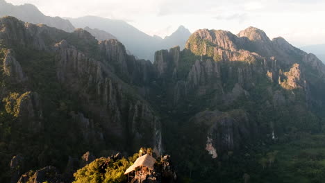 little bamboo hut on top of a mountain during sunset in laos with amazing view on green and sandy landscape