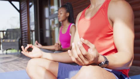 Happy-african-american-couple-doing-yoga-and-meditating-in-log-cabin,-slow-motion