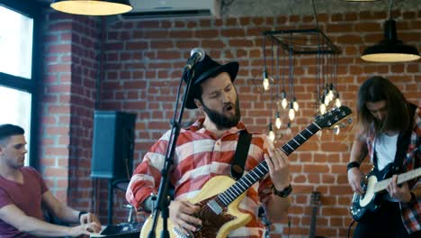 emotional bearded guitarist singing into microphone