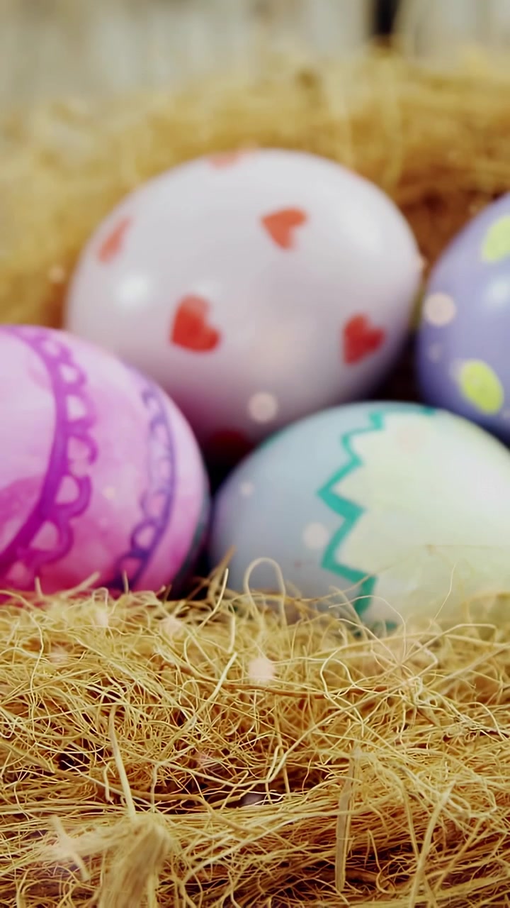 Vertical video: Pastel eggs in straw, camera pulling back, revealing patterns, bokeh for decor