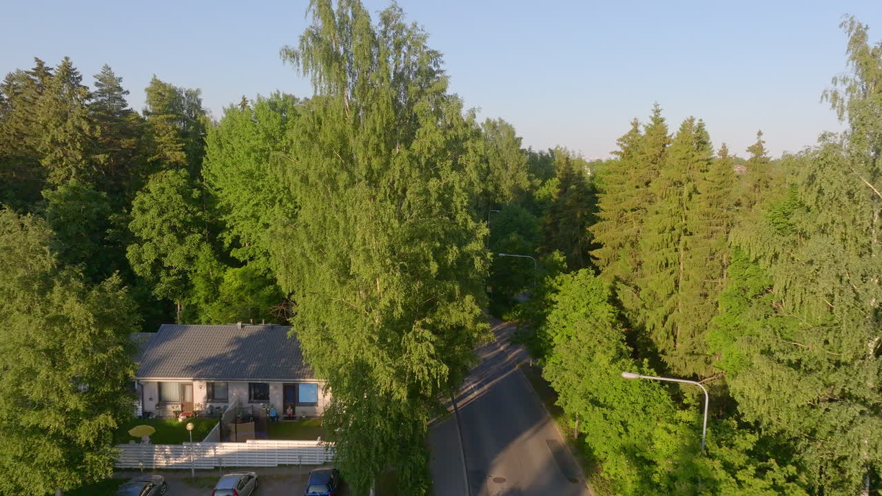 Aerial rising shot over sunlit trees, in the suburbs of Helsinki, Finland