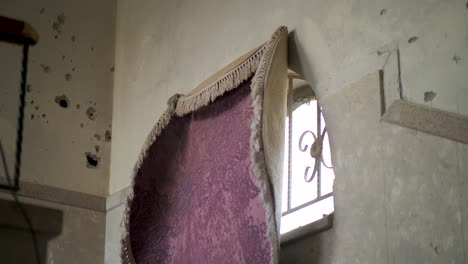 fixed indoor view of a patterned tapestry blocking a damaged wall opening in gaza.